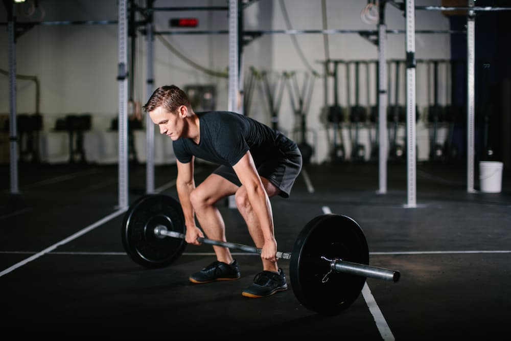 A man squats to pick up a barbell